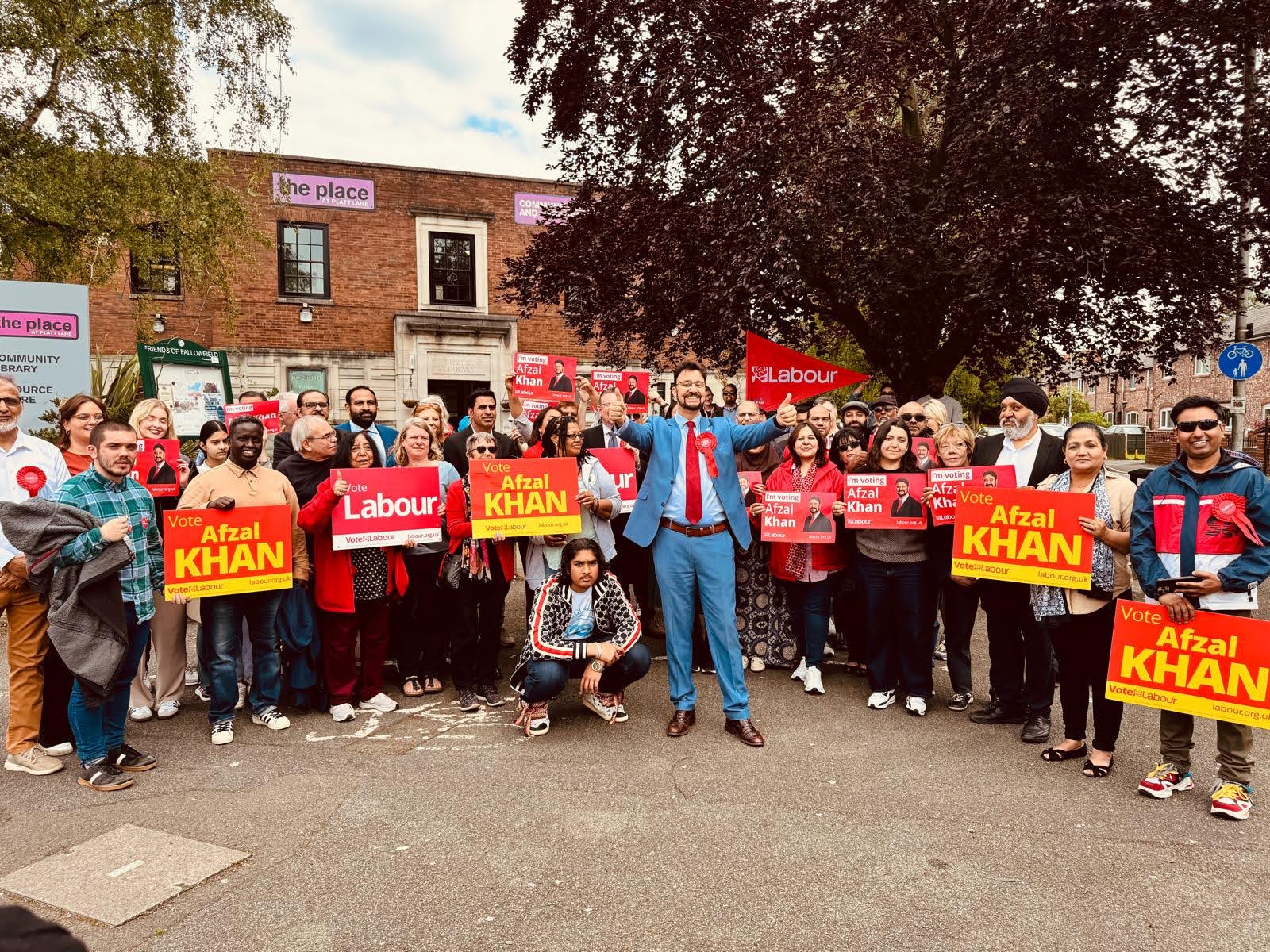 Afzal Khan MP and Labour campaigners holding signs that read 'Vote Afzal Khan' and 'Vote Labour'.
